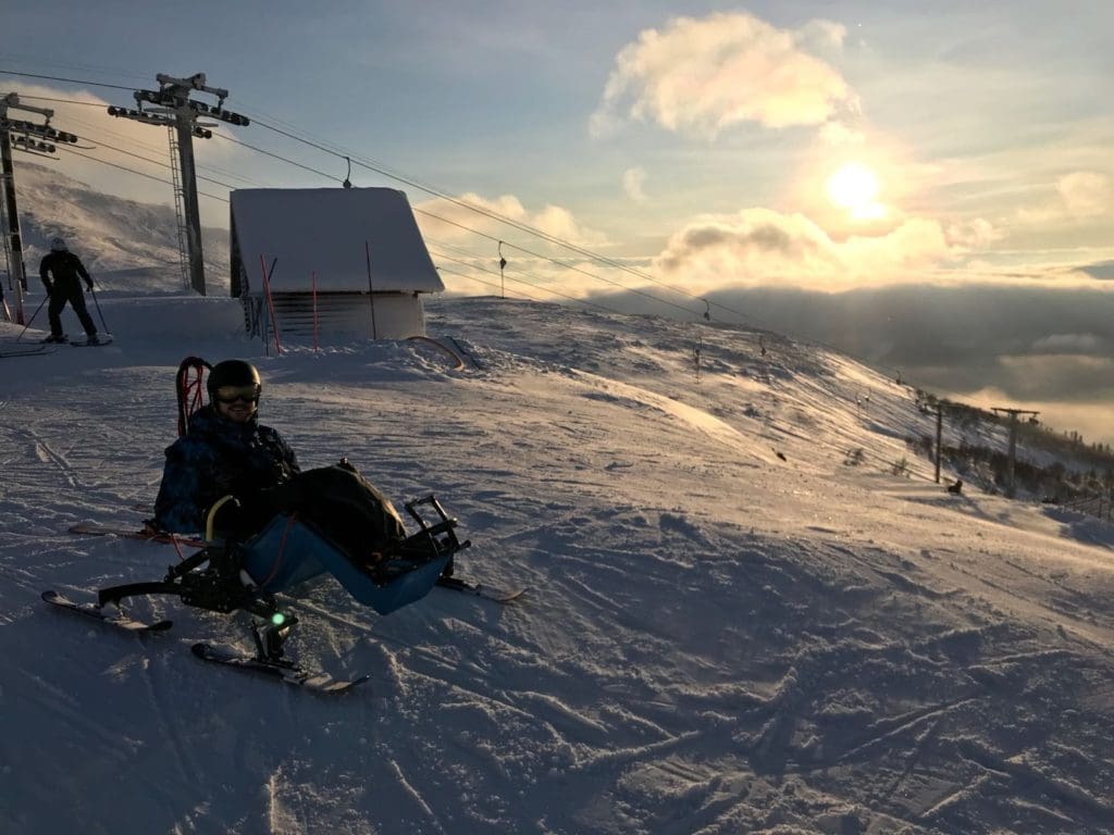 Ski-Karter on a ski top with sunny scenery in the background