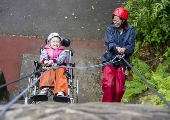 Young girl abseiling in her wheelchair at a Back Up Under 13s activity course