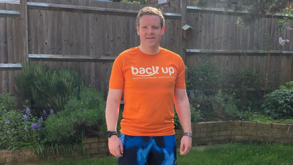 Sam wearing an orange Back Up t-shirt standing in a garden