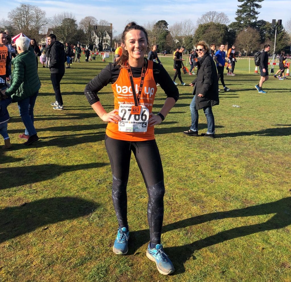 Melanie, wearing a Back Up vest, posing with her medal after the Hampton Court half marathon