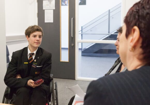 KEvin, a young person with a spinal cord injury, talking to a teacher