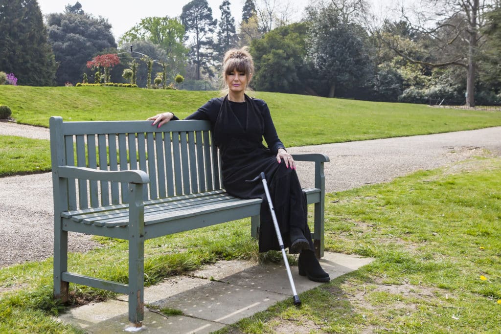 Tina, who experiences pain after spinal cord injury, sitting outside on a bench