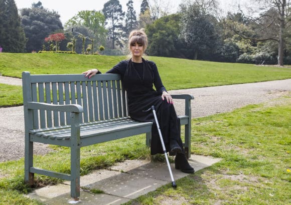 Tina, who experiences pain after spinal cord injury, sitting outside on a bench