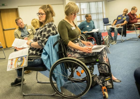 Two people sitting down looking at folders at a training weekend