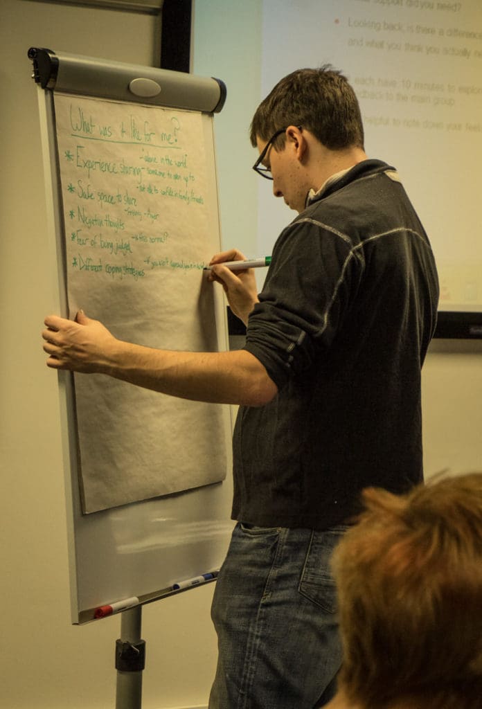 Andrew writes on a flipchart at a mentor training weekend 