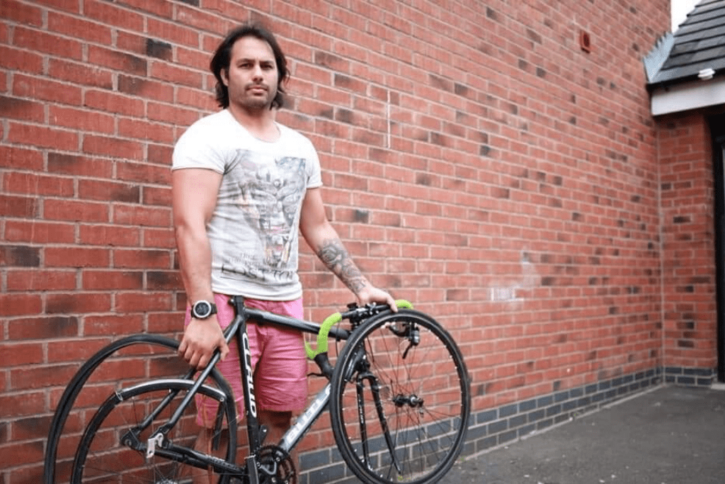 Adrian posing by a wall with a bike