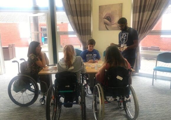 a group of young wheelchair users around a table