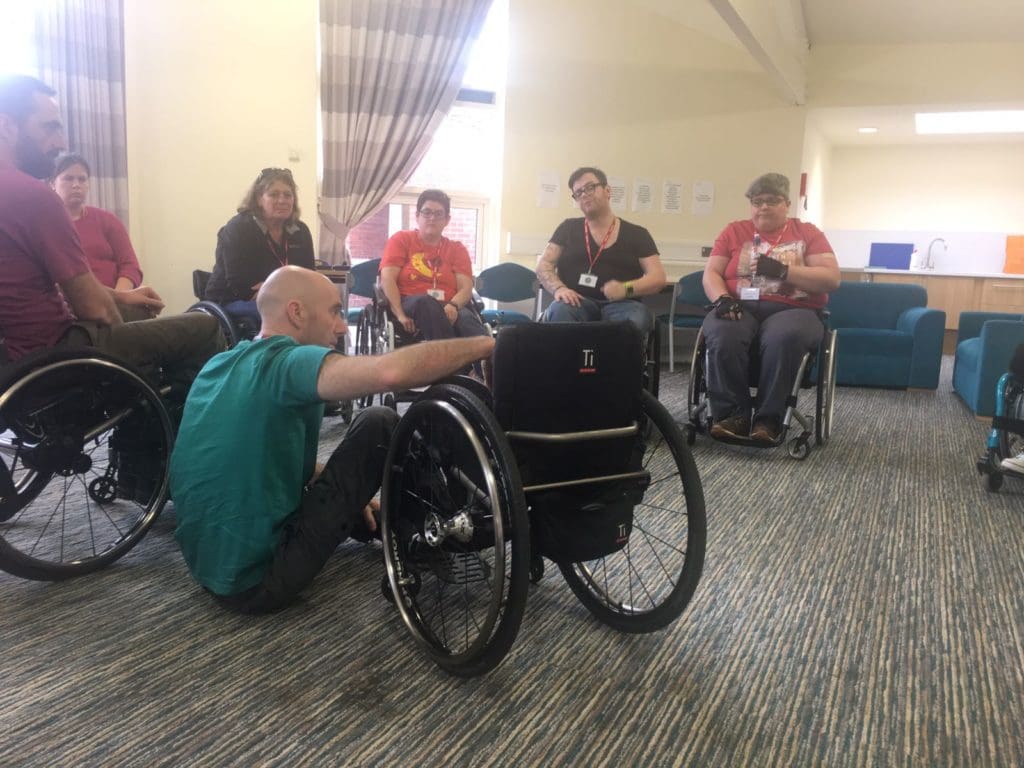 Trainer demonstrating floor to chair transfer on Skills for Independence course