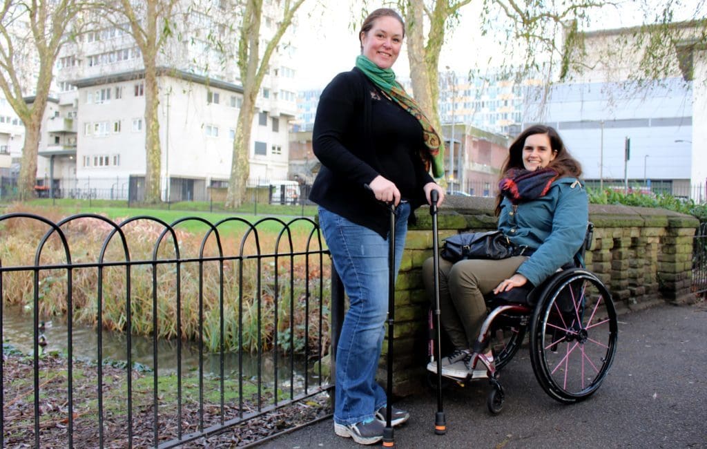 Two people with a spinal cord injury smiling in a park