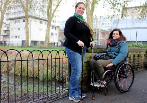 Two people with a spinal cord injury smiling in a park