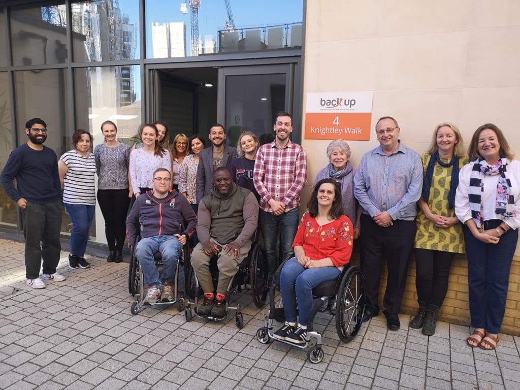 a group photo in front of the Back Up office of Valerie Singleton and the Back Up team. 