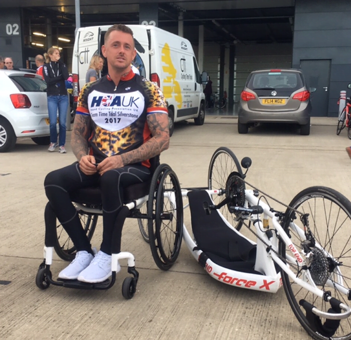 Andrew sits next to his handbike