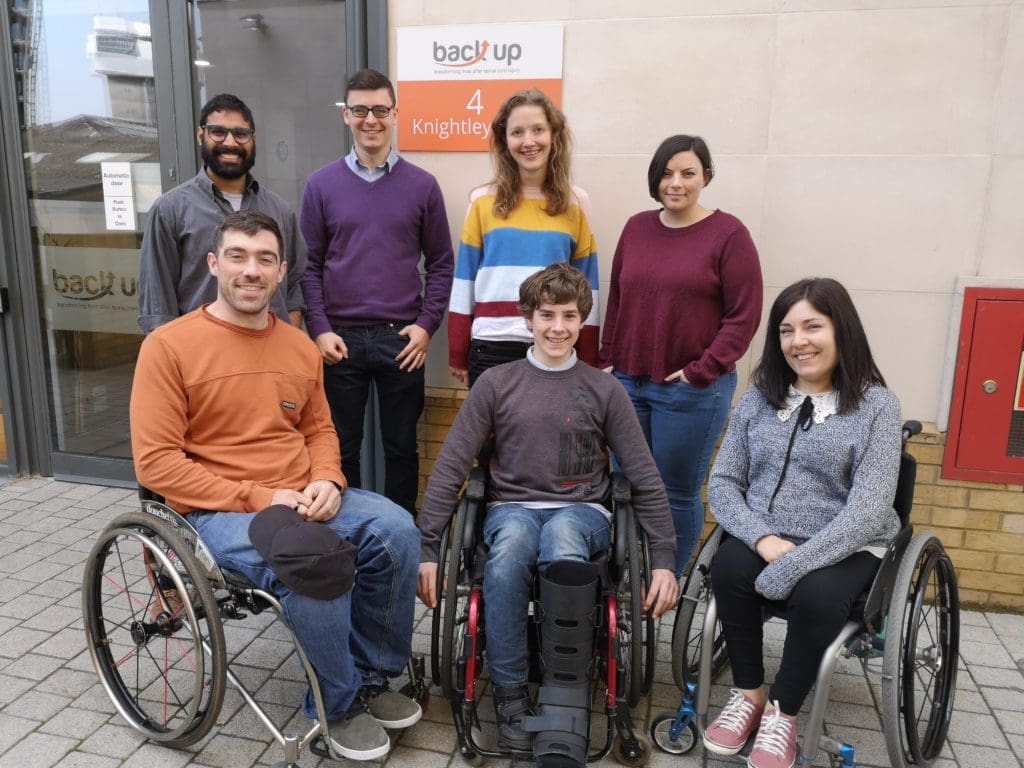 Kevin, a young spinal cord injured person, posing for a group photo with the Back Up staff during his work experience week