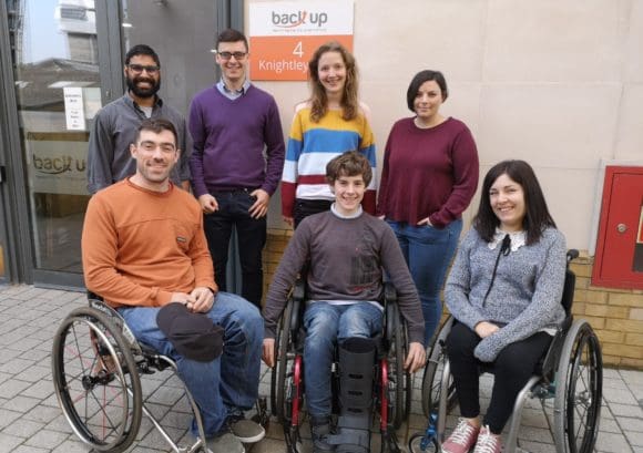 Kevin, a young spinal cord injured person, posing for a group photo with the Back Up staff during his work experience week