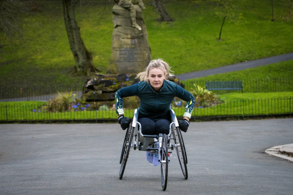 Photo of Melanie exercising in her racing chair - the featured image in her Three Marathons story