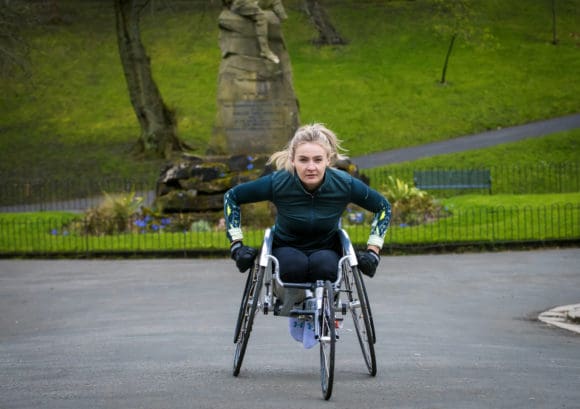 Photo of Melanie exercising in her racing chair - the featured image in her Three Marathons story