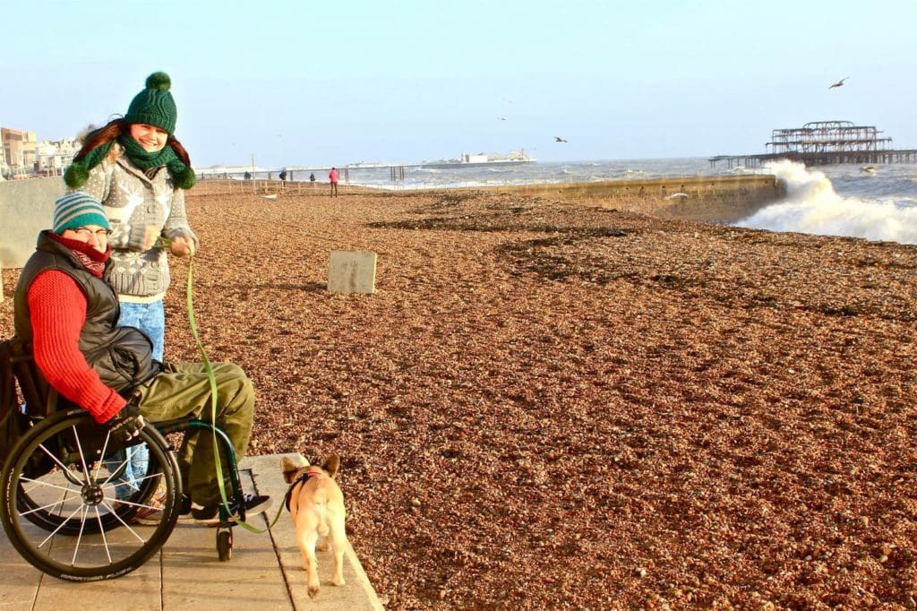 Luke, his wife and dog smile on a beach