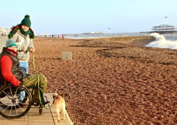 Luke, his wife and dog smile on a beach