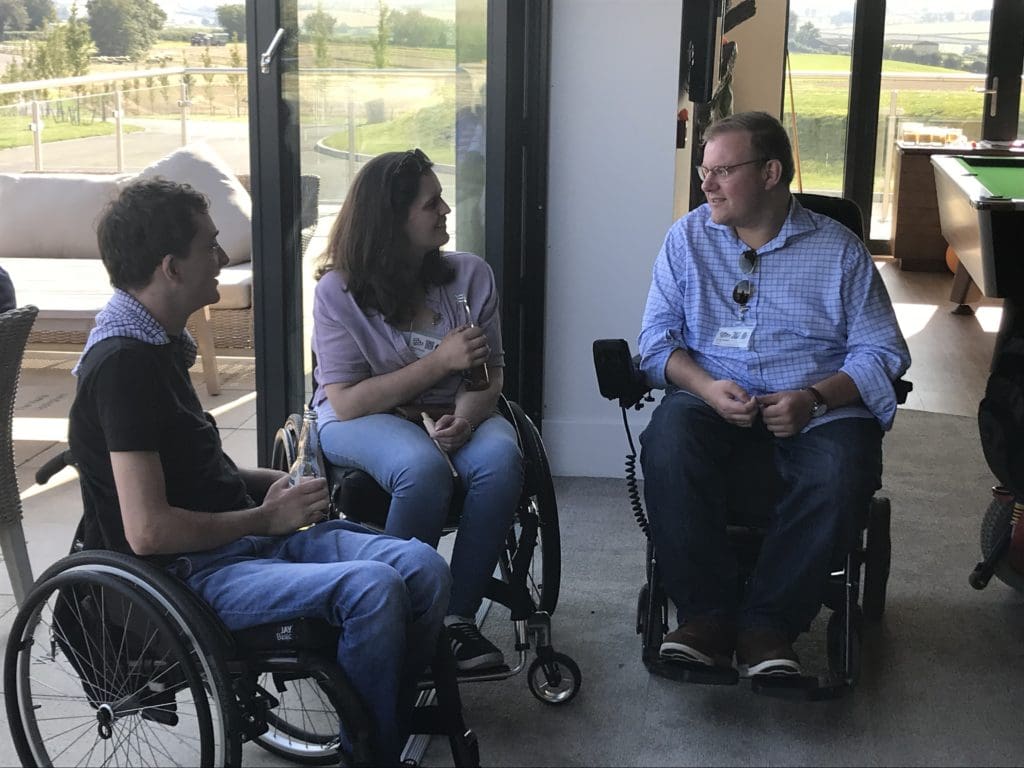 Two manual wheelchair users and a powerchair user having a chat