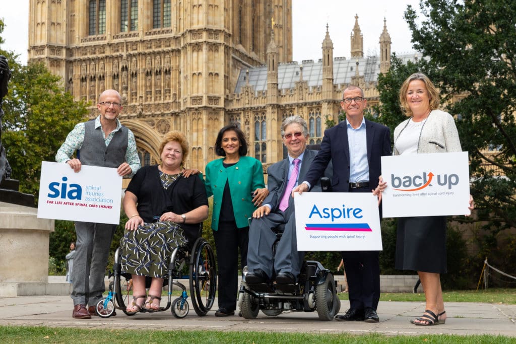 The CEOs and chairs of Back Up, Aspire, and SIA stood together outside the house of commons holding banners with the names of each charity
