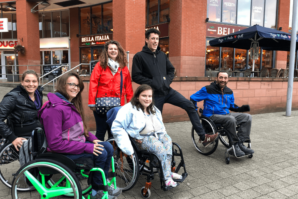 Laura, a young volunteer, posing with a group of wheelchair users