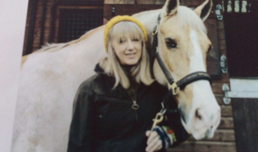 Jill, someone with an incomplete spinal cord injury who can walk without aids, posing with a horse