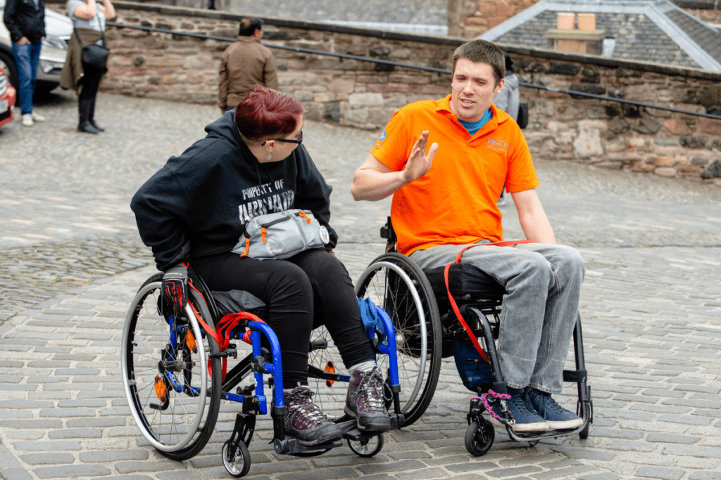 Two wheelchair users on a cobbled street - you can learn how to tackle obstales like this using our wheelchair skills app