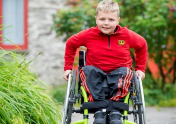 A YOUNG WHEELCHAIR USER PUSHING TOWARDS THE CAMERA