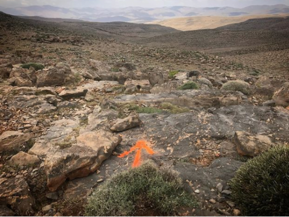 A rocky part of the ultra marathon path with an orange arrow marking the way