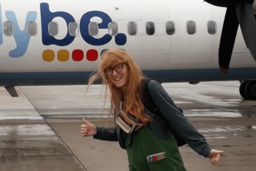 Holly, a spinal cord injured person who can walk without aids, posing in front of a plane