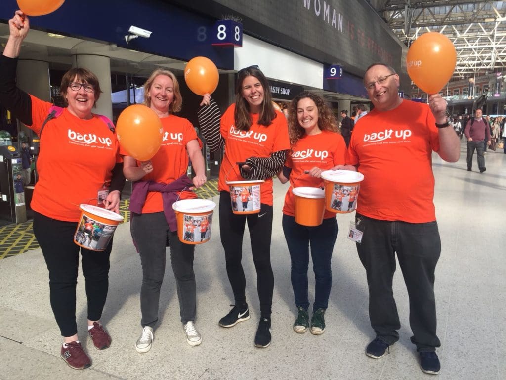 five Back Up volunteers holding balloons at London Waterloo bucket collection