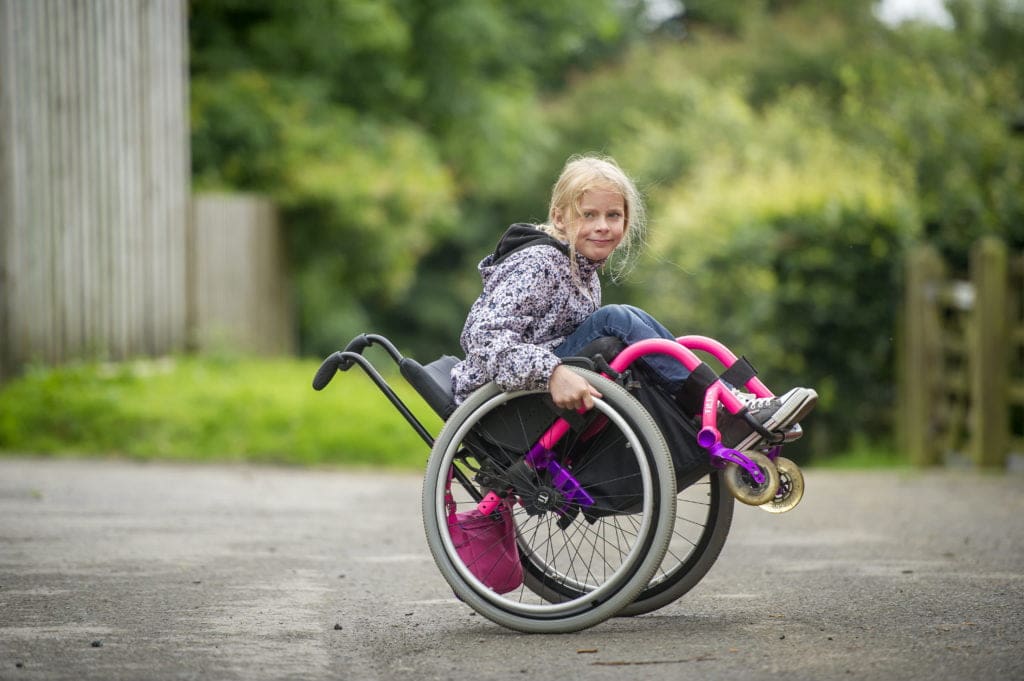 Young wheelchair user doing a back wheel balance