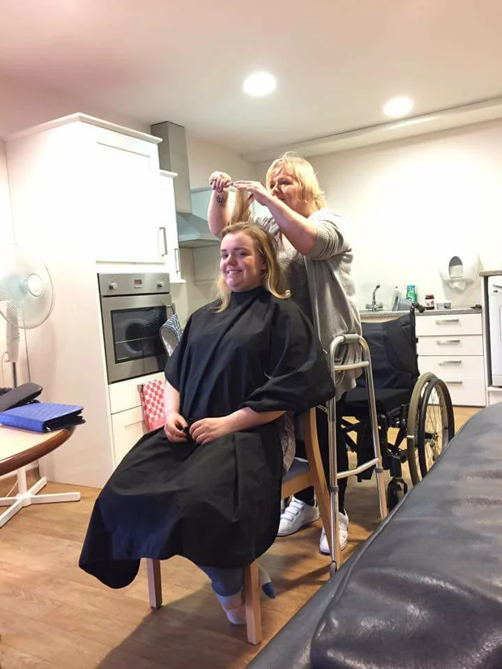 Fiona stands while cutting someone's hair